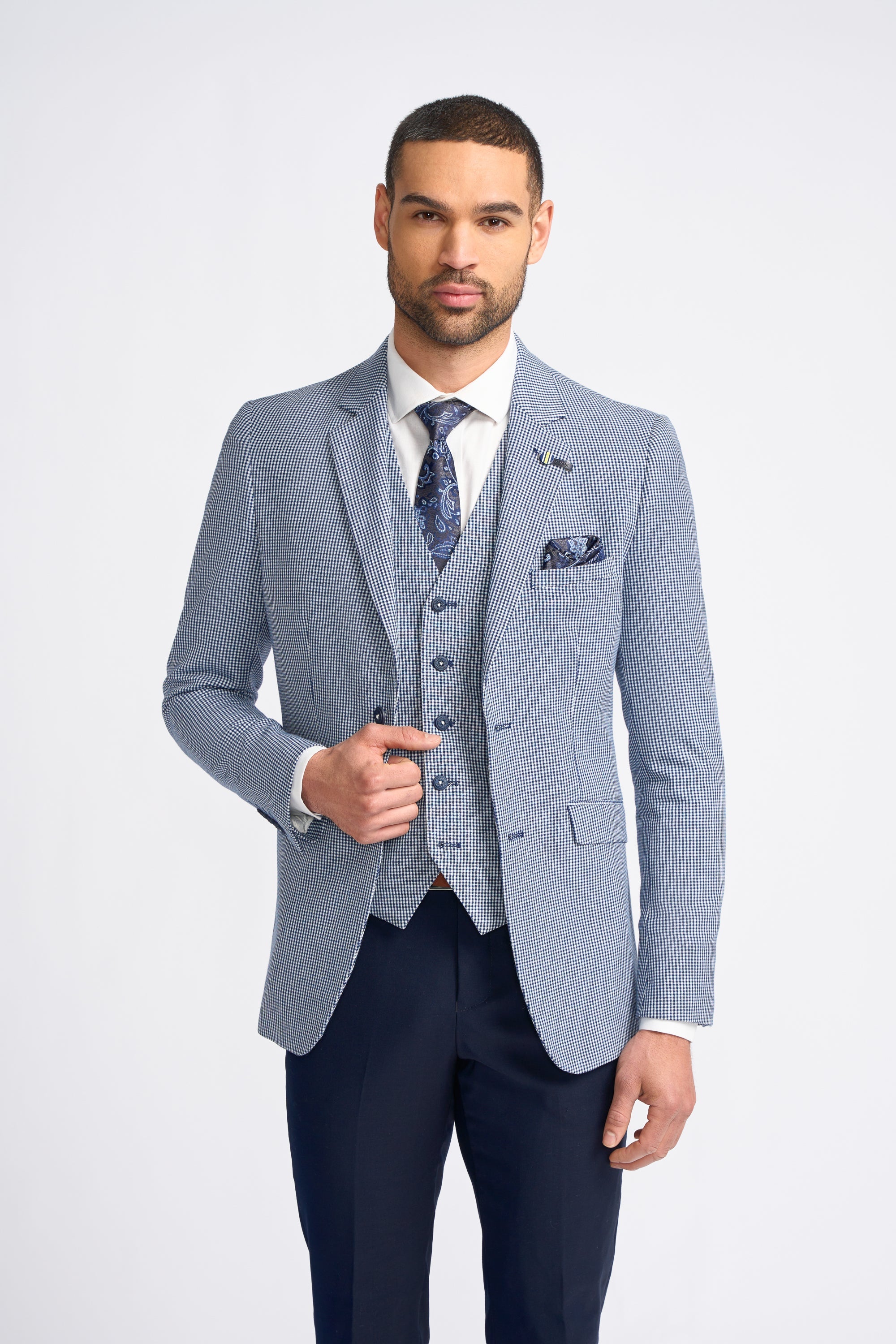Man wearing a light blue checkered suit with a white shirt and patterned tie on a white background