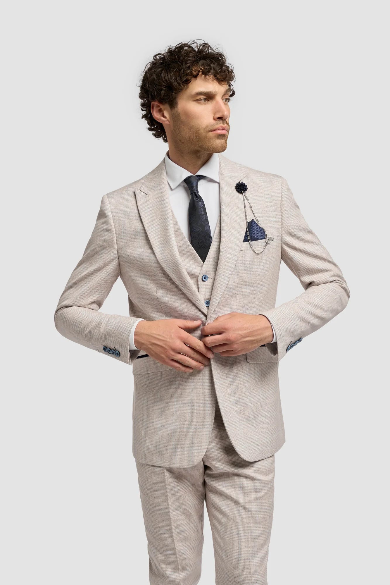 Man wearing a beige suit with a black tie on a white background